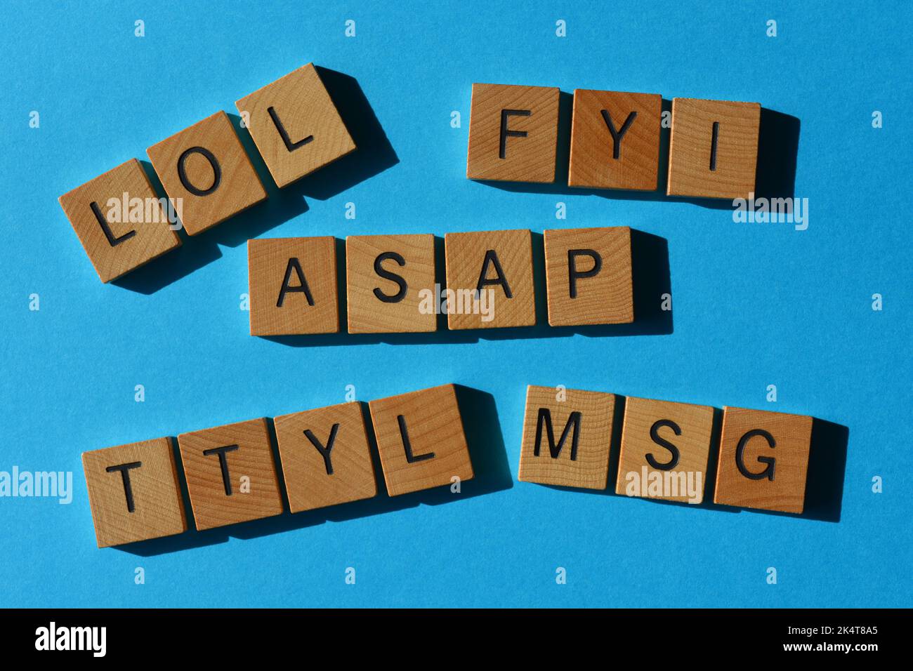 LOL, FYI, ASAP, TTYL, MSG, les acronymes utilisés dans le texte parlent en lettres de l'alphabet en bois isolées sur fond bleu Banque D'Images