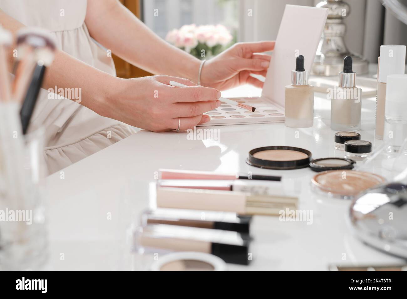 Table de maquillage, cosmétiques décoratifs pour le maquillage professionnel et domestique. Vue rapprochée des pinceaux et des fards à paupières dans un salon blanc ensoleillé. Artistes de beauté Banque D'Images