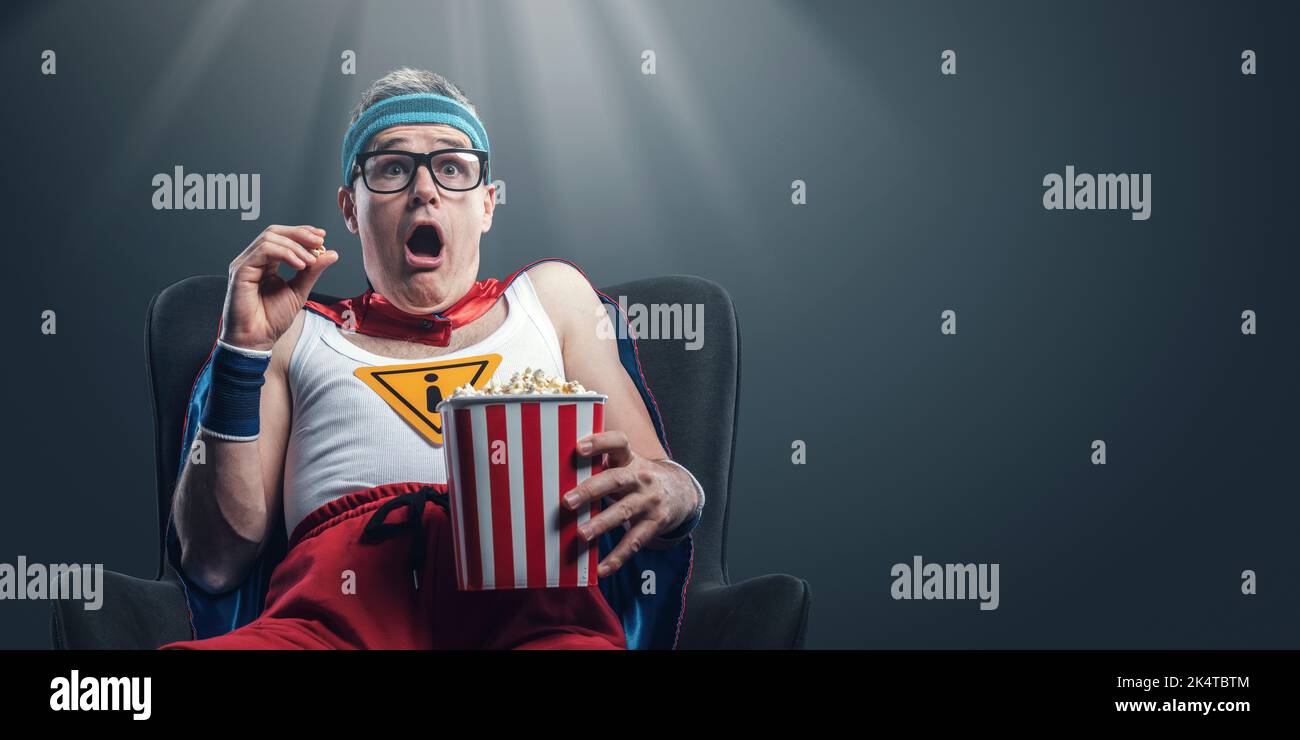Super-héros drôle regardant des films d'horreur et mangeant du pop-corn, il est terrifié Banque D'Images