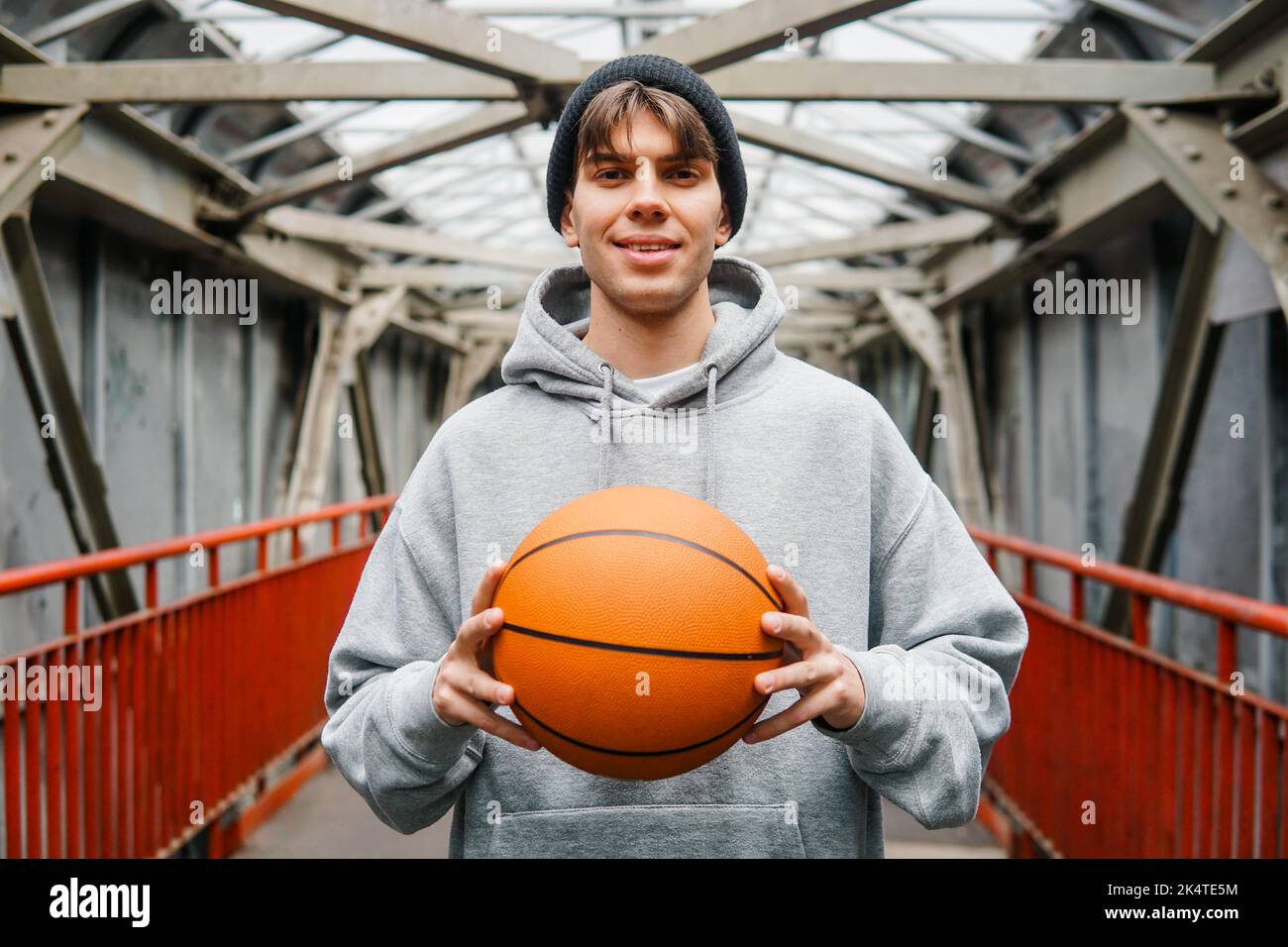 Un jeune sportif tient le ballon de basket-ball sur fond urbain. Concept de mode de vie actif. Banque D'Images