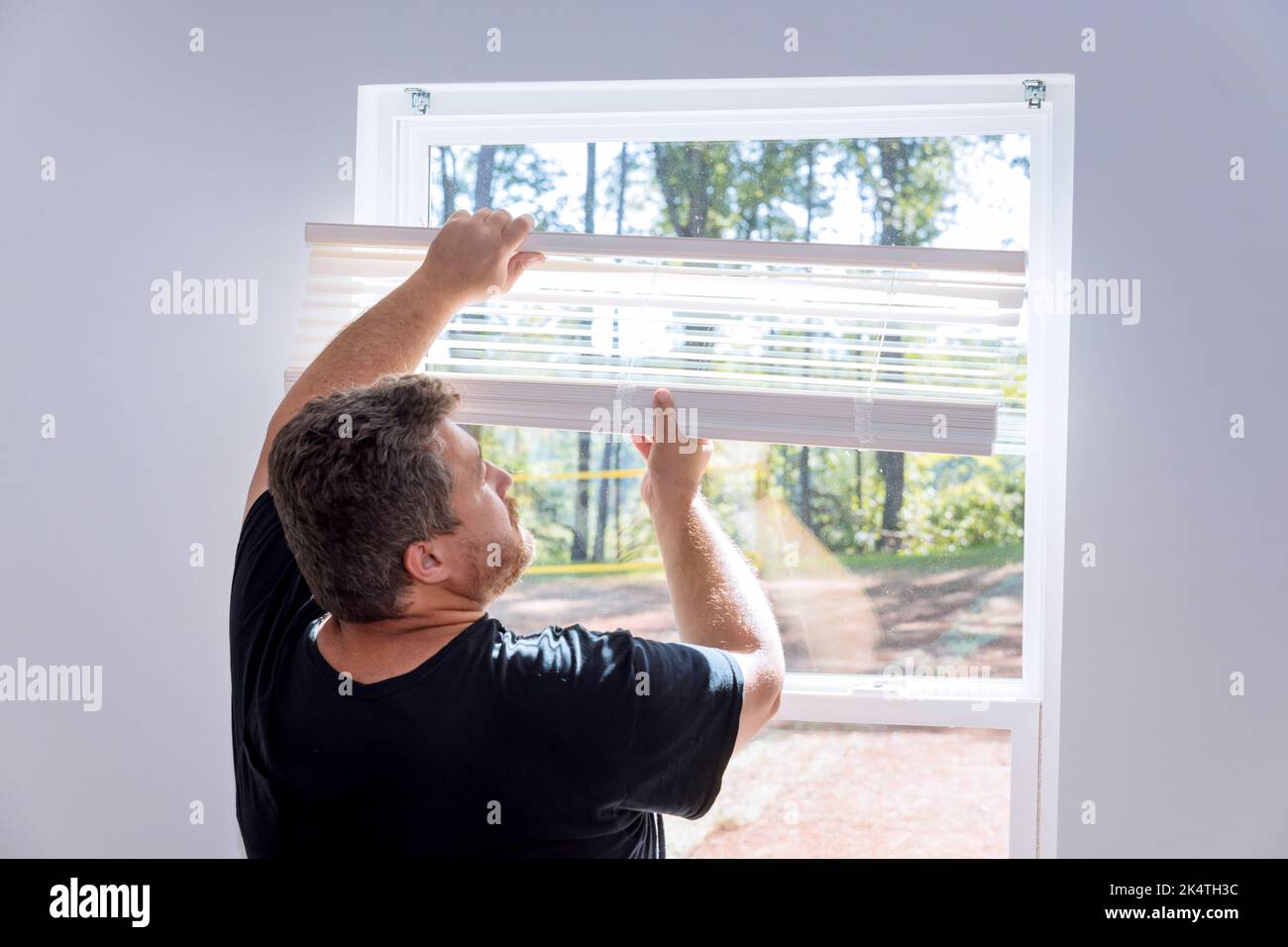 Dans une maison nouvellement construite, un entrepreneur installe des stores de fenêtre Banque D'Images