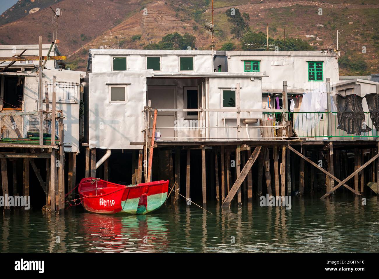 Un canot chinois traditionnel rouge amarré à l'extérieur d'une maison de pang uk, ou de pilotis, à Tai O, sur l'île Lantau, à Hong Kong Banque D'Images