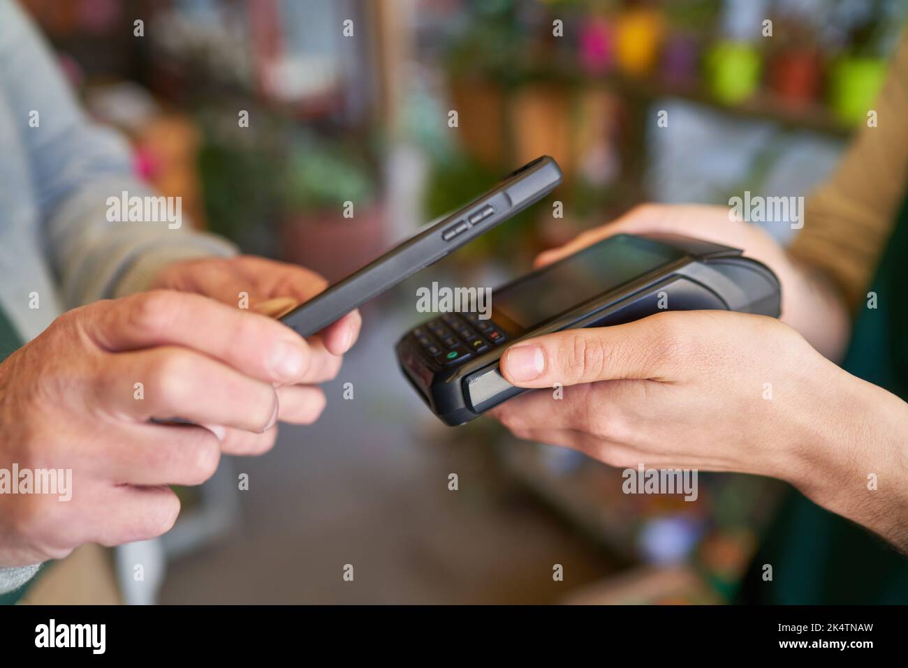 Mains tenant le smartphone et le terminal de carte NFC pour le paiement mobile dans la vente au détail Banque D'Images