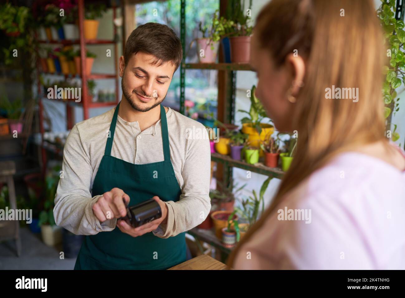 Fleuriste avec un terminal de carte et un client effectuant des paiements sans contact dans le fleuriste Banque D'Images
