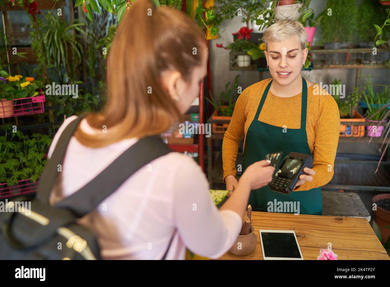 Le client de la boutique de fleurs à la caisse effectue un paiement mobile avec une carte de crédit sur le lecteur NFC Banque D'Images