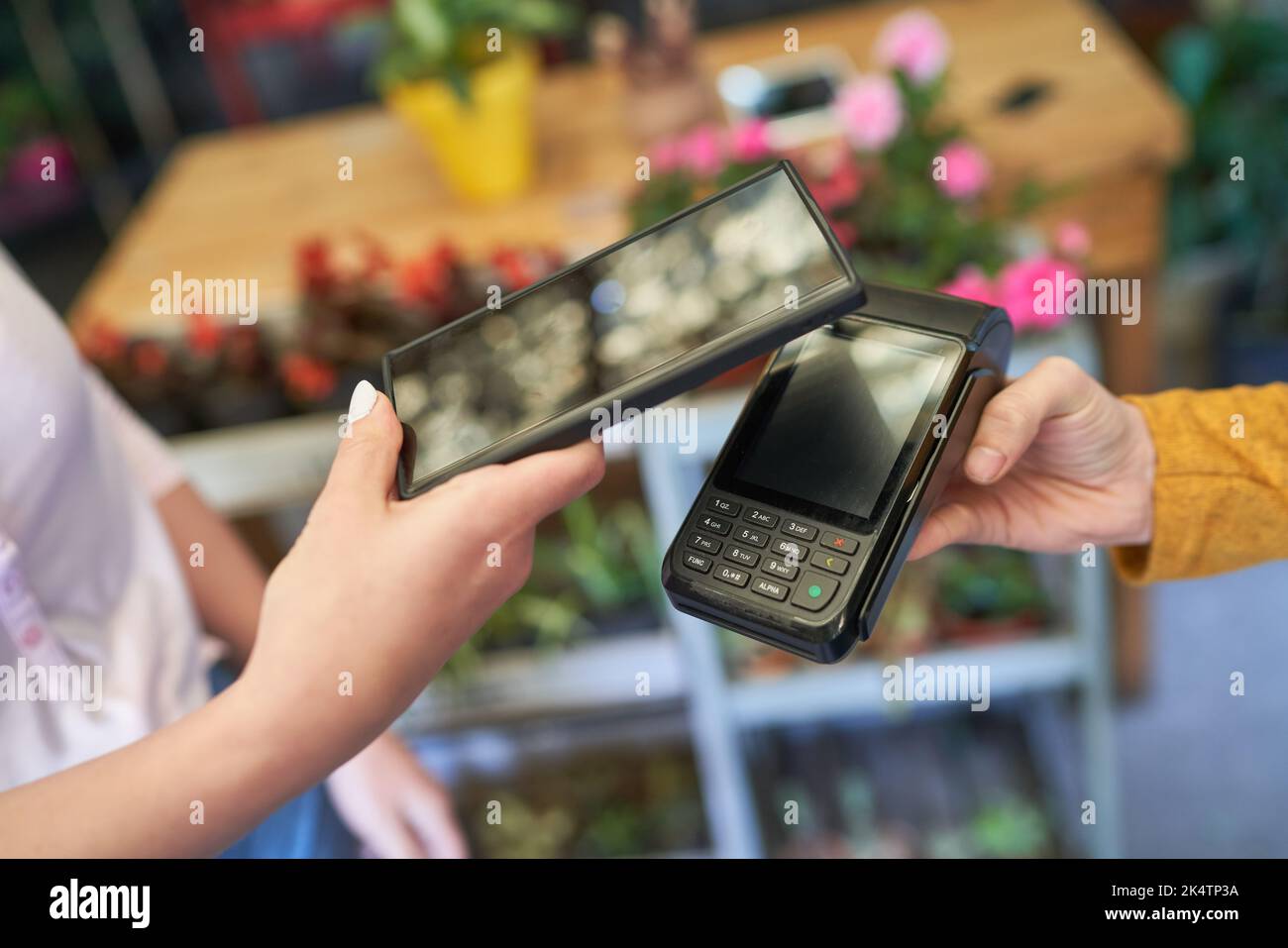 Le client paie sans contact avec son téléphone mobile au lecteur NFC de la boutique de fleurs Banque D'Images