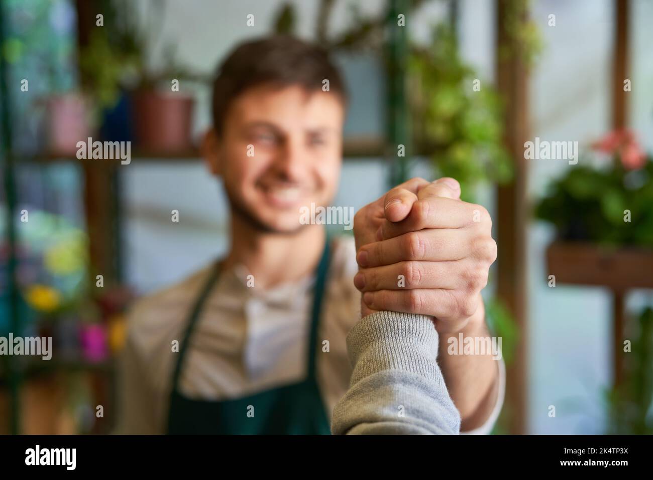 Jeune fleuriste faisant la poignée de main fraîche comme concept de coopération et de félicitations Banque D'Images
