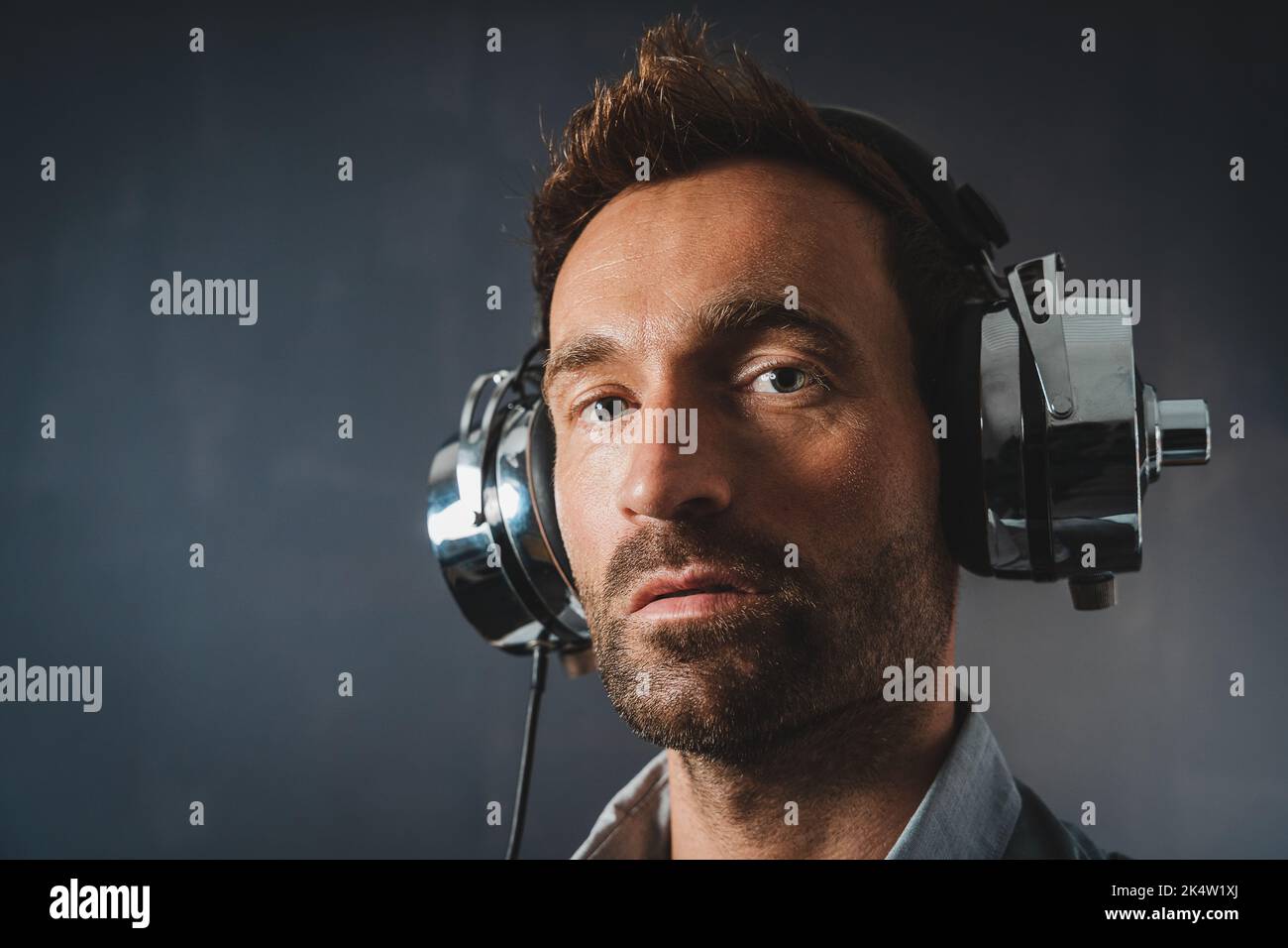 Portrait d'un homme attrayant portant un casque rétro de grande taille en matériau argenté brillant Banque D'Images