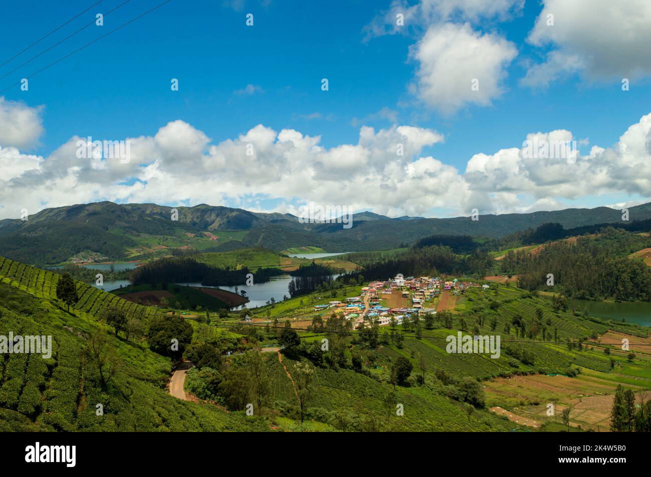 Montagnes imposantes, plantations de thé, rivière avec petites maisons visibles, ciel bleu et blanc, reflet visible dans l'eau, cadeau de la nature de verdure chaque Banque D'Images