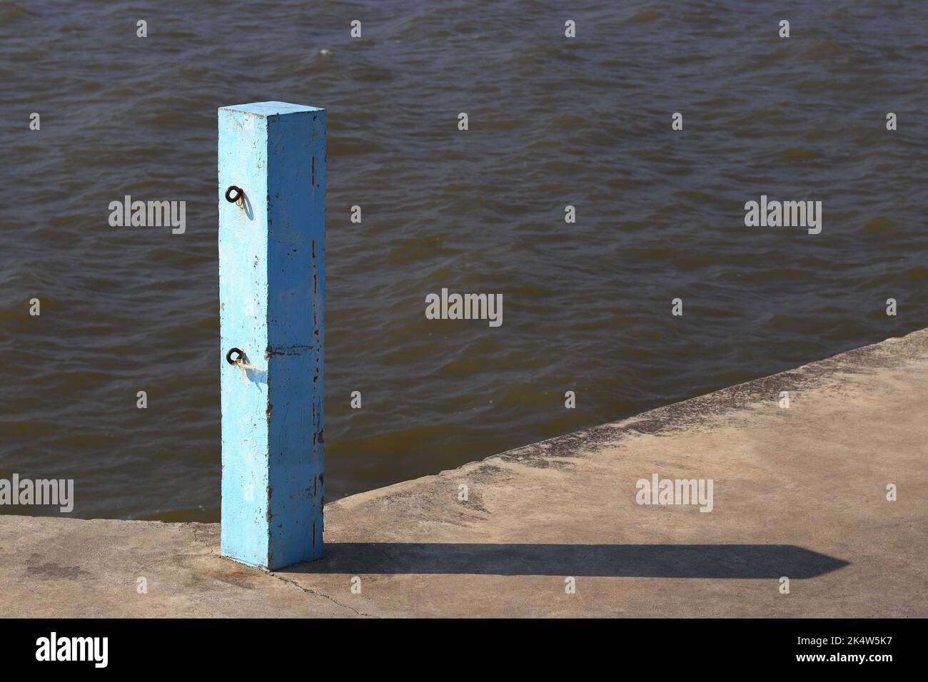 Poteau en béton avec crochets à chaînes sur la jetée, poteau bleu Jetty, piliers en béton bleu avec lumière du soleil. Banque D'Images