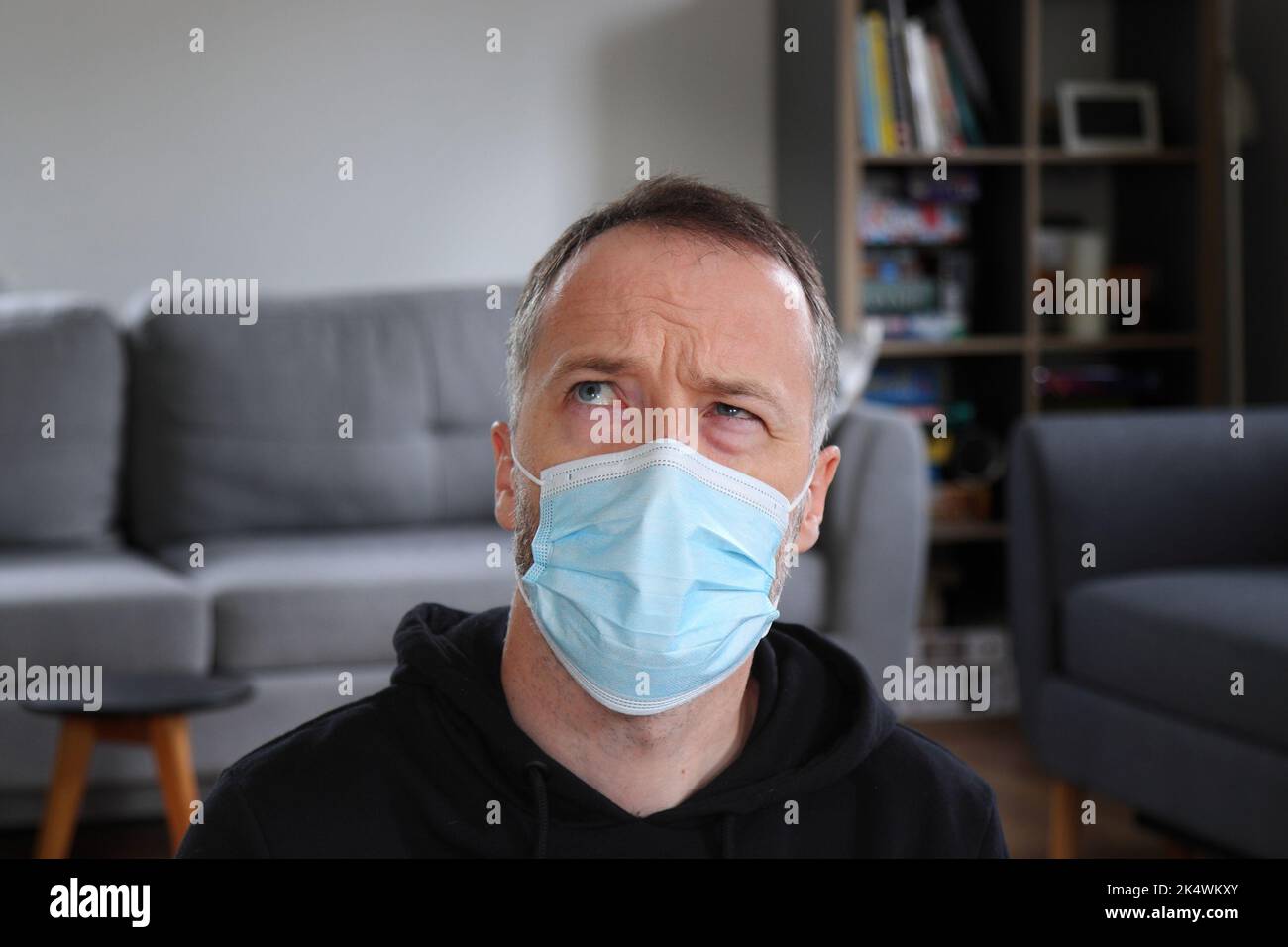 Homme pensant. Personne concentrée faisant une pensée lourde dans le masque de visage. Homme barbu portant un pull à capuche noir décontracté. Homme de race blanche adulte en 30s ou 40s. Banque D'Images