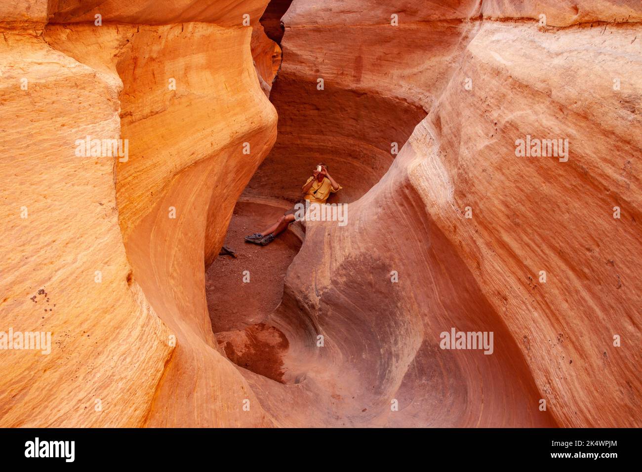 Un randonneur prend une photo dans le canyon de Holeman Slot sculpté par l'eau qui coule pendant des milliers d'années dans le parc national de Canyonlands, Utah Banque D'Images