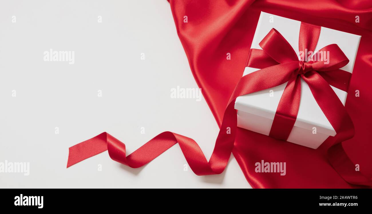 Boîte cadeau avec ruban rouge décoration en toile de satin, espace blanc vide.Cadeau de Saint-Valentin, cadeau de Noël Banque D'Images