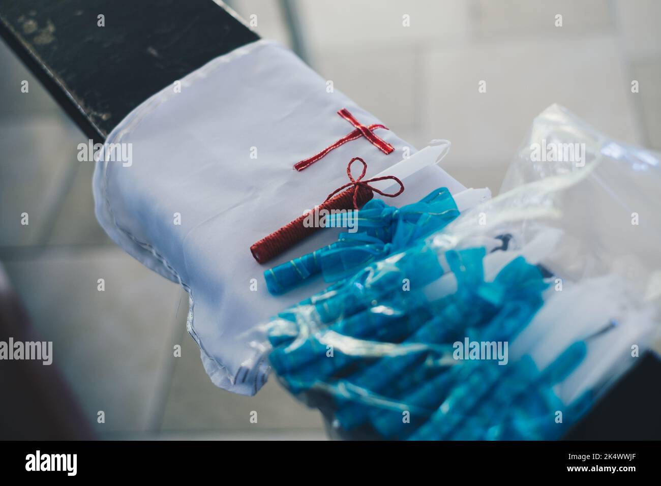 Robe blanche sans manches en satin pour enfant et bougie avec ficelle rouge sur le dessus, posée sur le pew pour le baptême ou la célébration chrétienne Banque D'Images