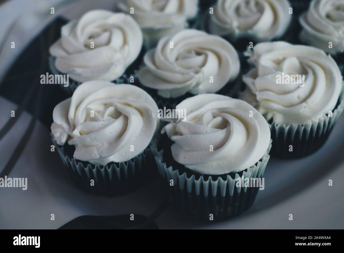 Bouquet de délicieux petits gâteaux au chocolat avec garniture à la crème blanche à la vanille sur une assiette de service blanche. Mise au point sélective. Banque D'Images