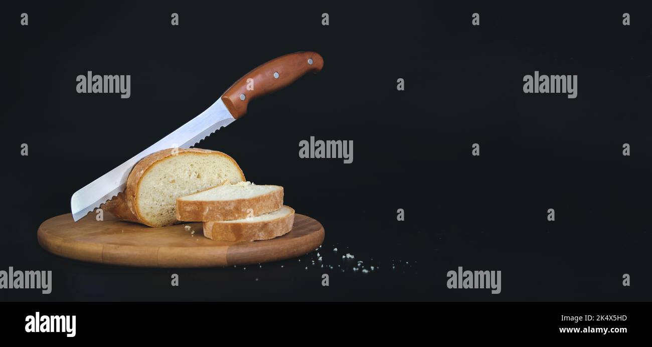 Pain fraîchement cuit, tranches de pain et couteau tranchant sur bois rustique. Banque D'Images