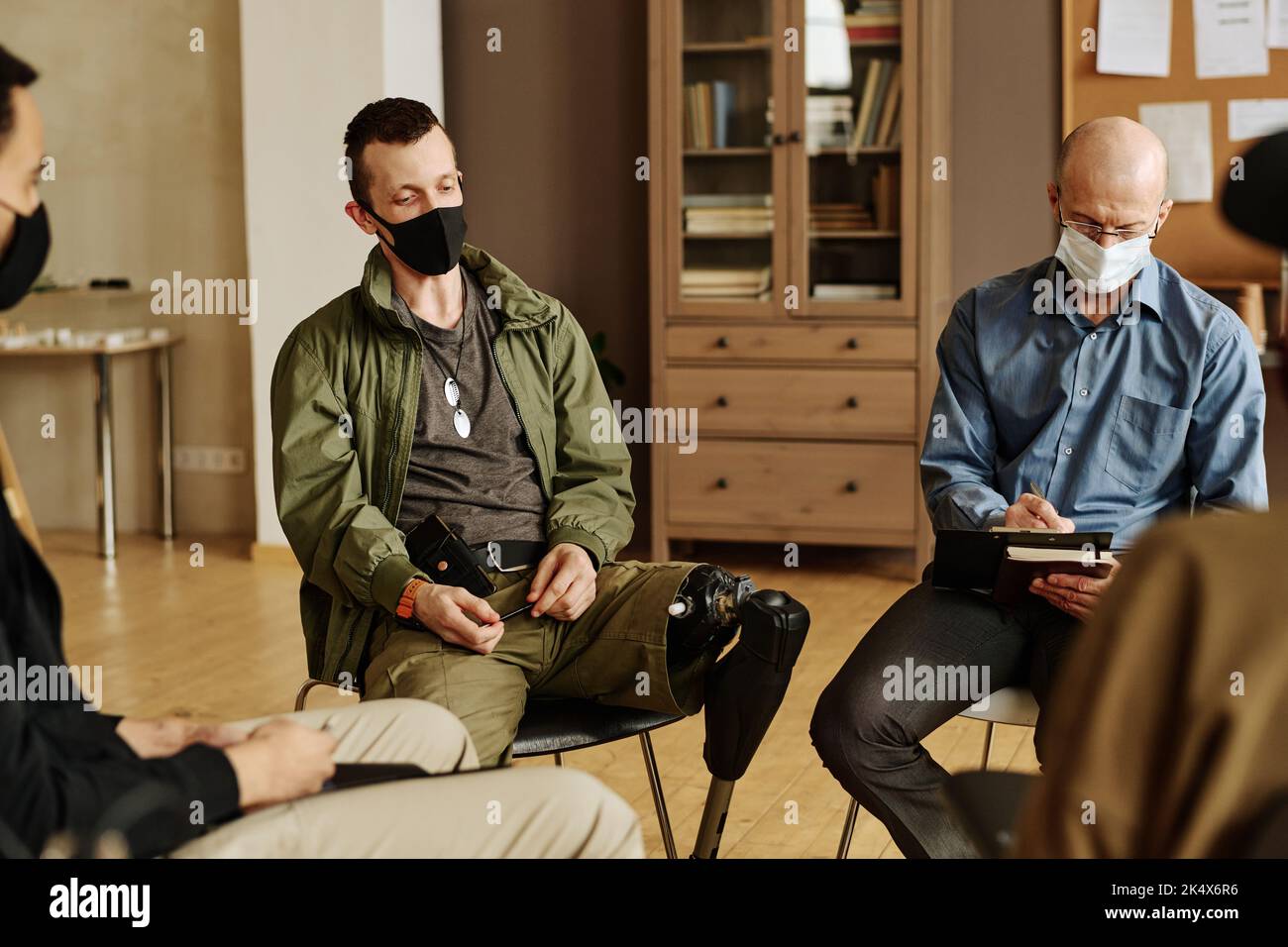 Jeune homme avec prothèse de jambe assis parmi le conseiller et d'autres personnes avec le syndrome post-traumatique et de raconter son histoire Banque D'Images