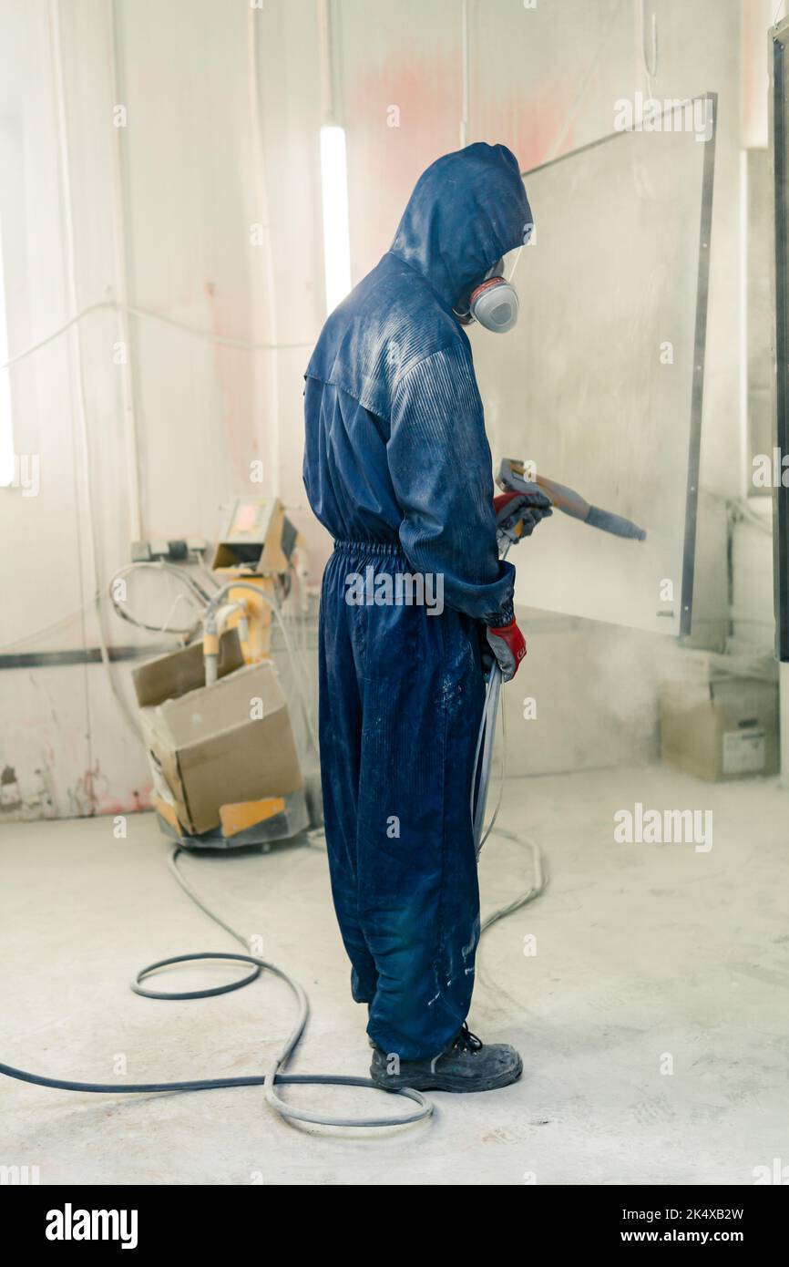 Perm, Russie - 21 septembre 2022: Poudre ouvrier couvre des pièces d'acier dans une cabine de pulvérisation Banque D'Images