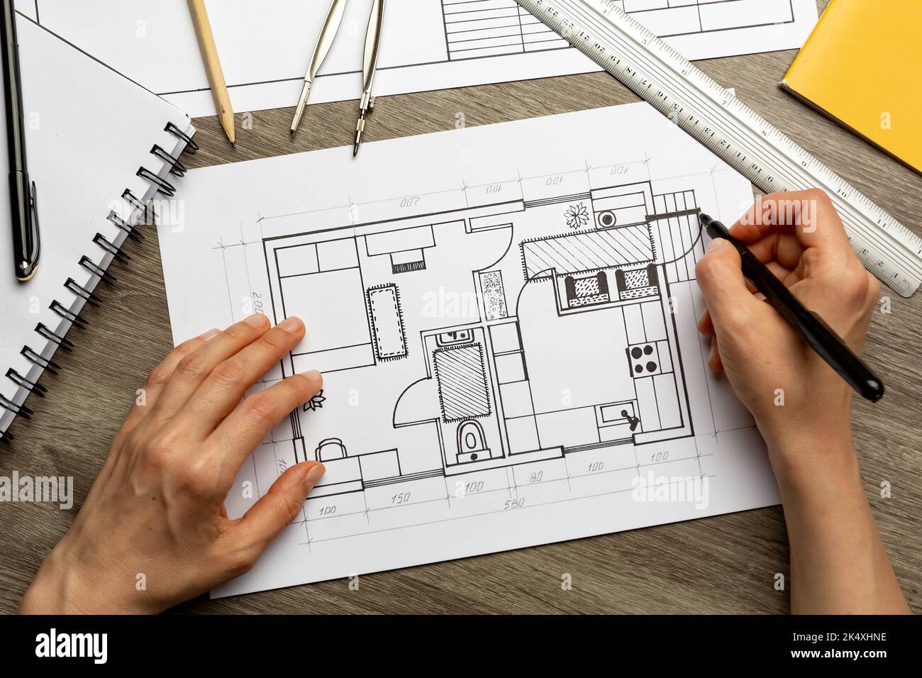 Le concepteur dessine une esquisse de l'intérieur sur du papier sur le bureau. Modèles. Banque D'Images