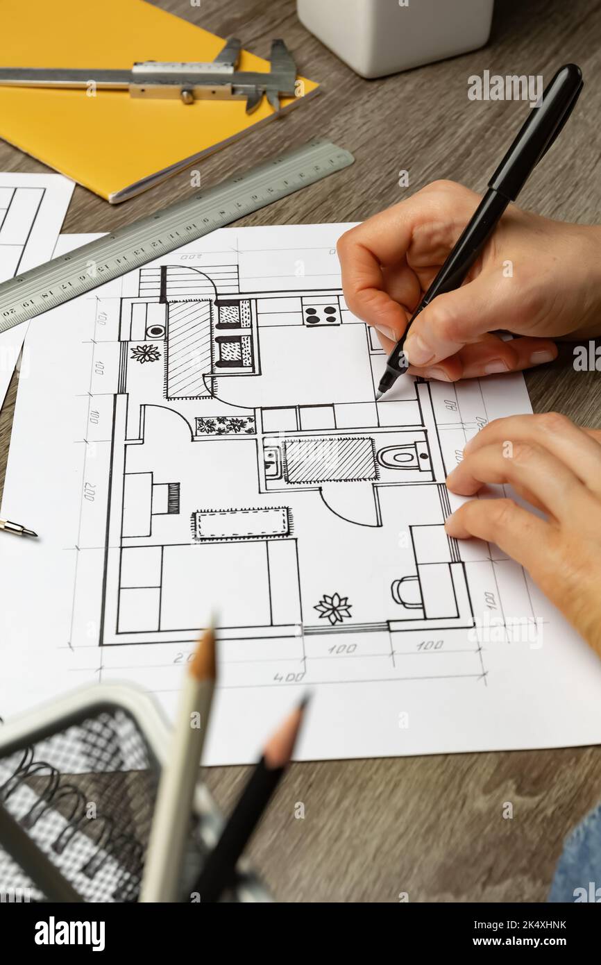 Le concepteur dessine une esquisse de l'intérieur sur du papier sur le bureau. Modèles. Banque D'Images