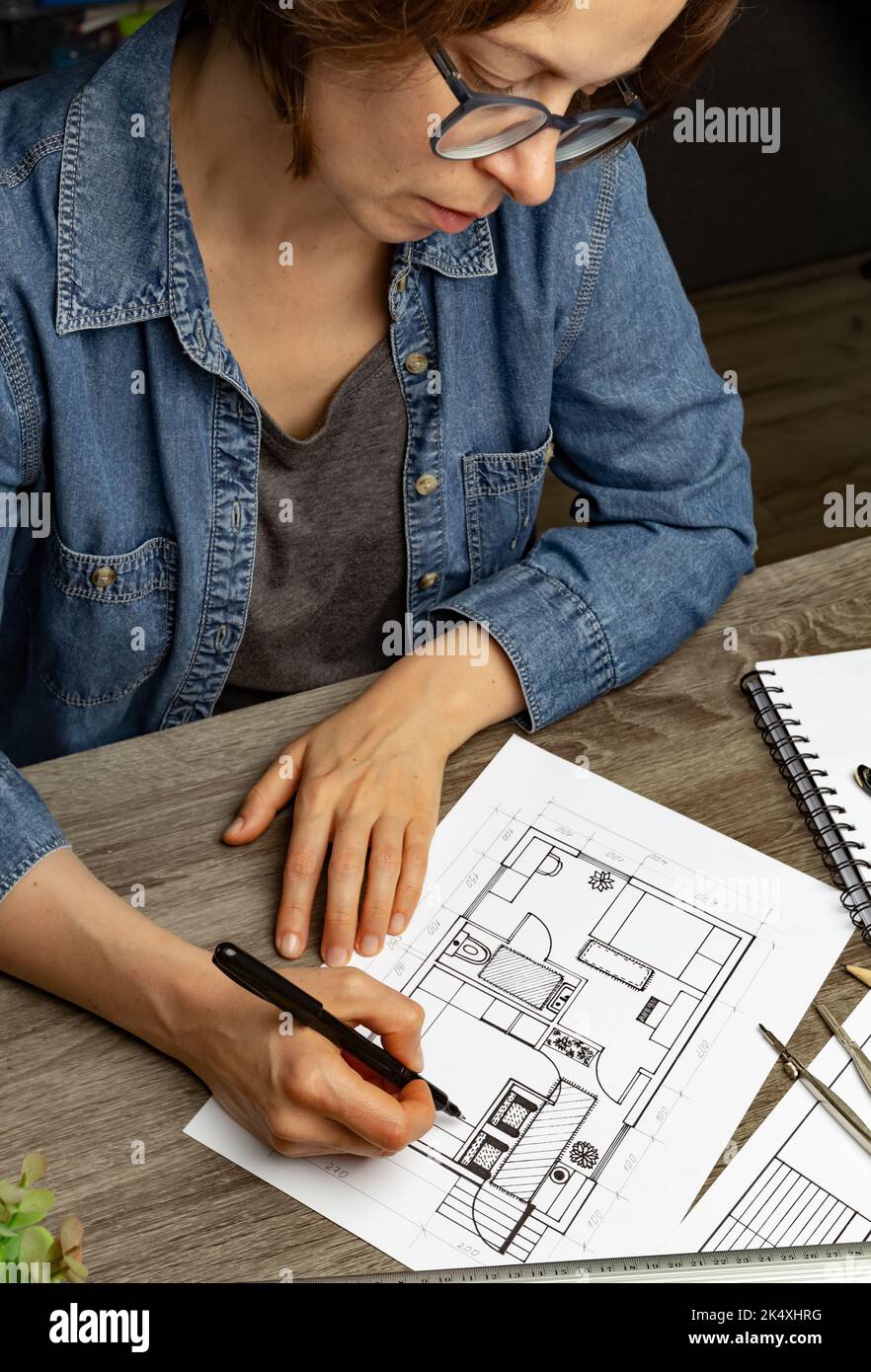 Le concepteur dessine une esquisse de l'intérieur sur du papier sur le bureau. Modèles. Banque D'Images
