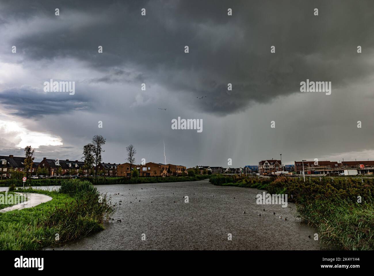 Des nuages et des éclairs spectaculaires frappent au cours d'un orage avec de fortes pluies dans l'eau d'un étang Banque D'Images