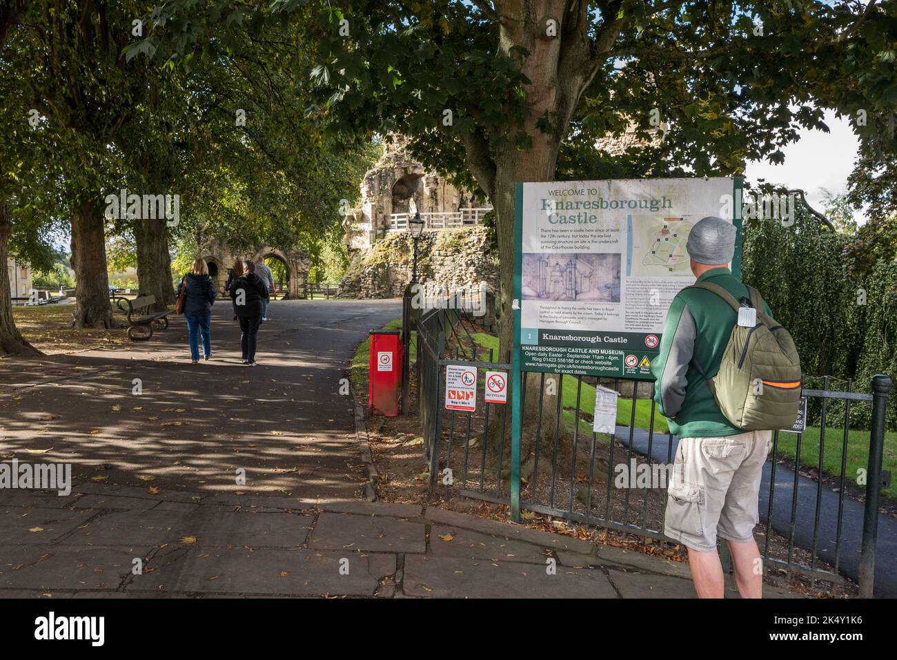 Homme regardant le panneau d'affichage de l'information à l'extérieur des ruines acientes du château de Knaresborough, Knaresborough, Yorkshire, Angleterre. Banque D'Images