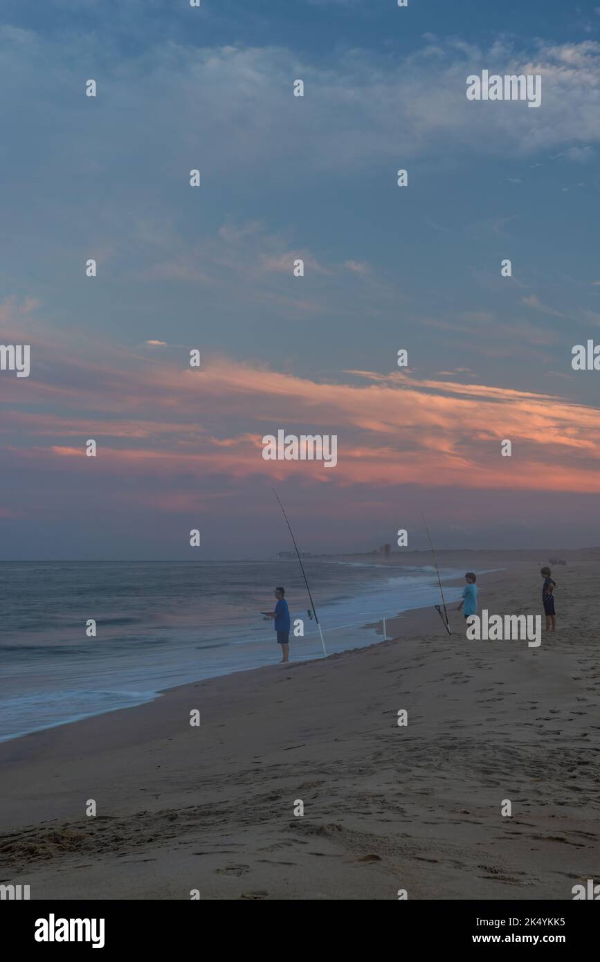 3 personnes surfent sur la pêche au coucher du soleil, parc national de Cape Henlopen, Delaware Banque D'Images