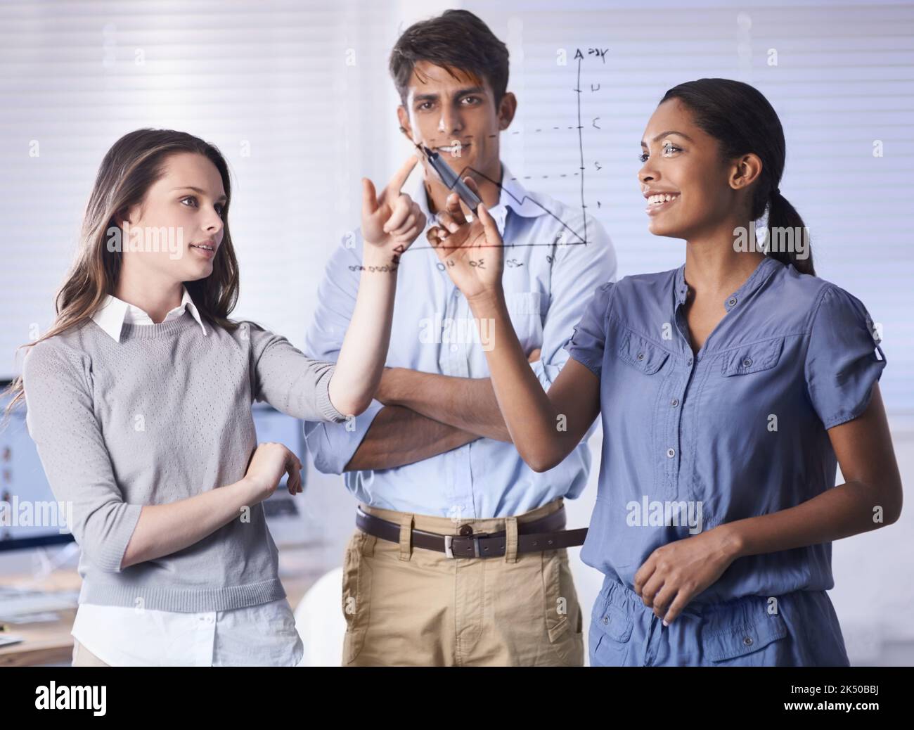 Élaborer des stratégies pour assurer la croissance de l'entreprise. Un groupe de jeunes hommes d'affaires qui dessinant un graphique sur une fenêtre en verre. Banque D'Images