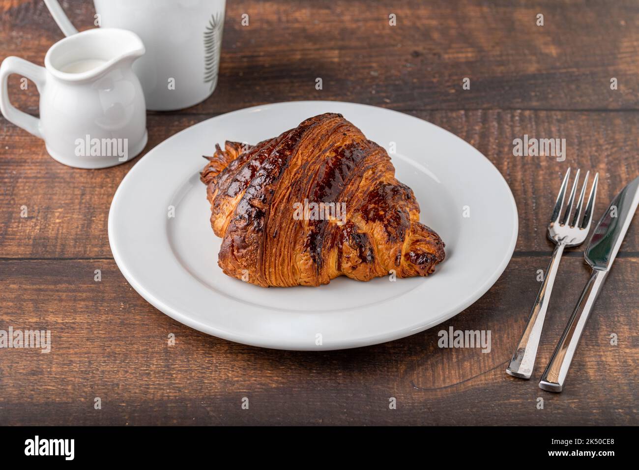 Croissant avec café à côté sur une table en bois Banque D'Images