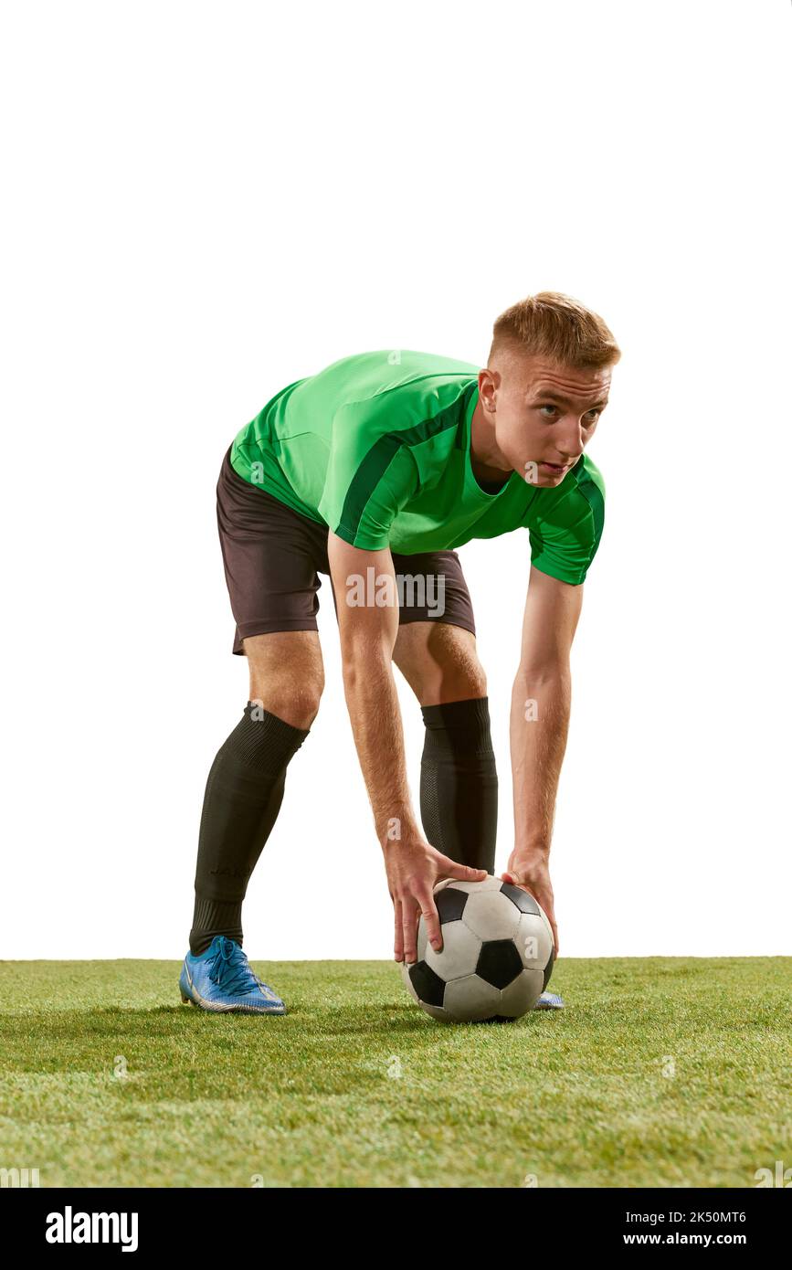 Un jeune homme, joueur professionnel de football entraînement isolé sur fond blanc studio. Concept d'action, d'énergie, de sport. Banque D'Images