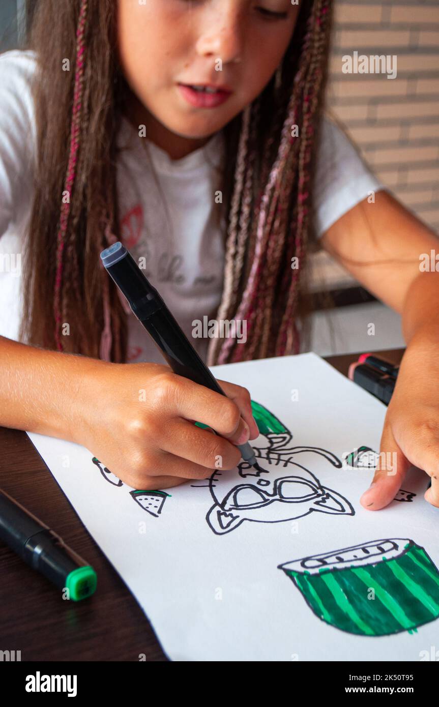 Une petite fille heureuse dessine avec des marqueurs. Banque D'Images