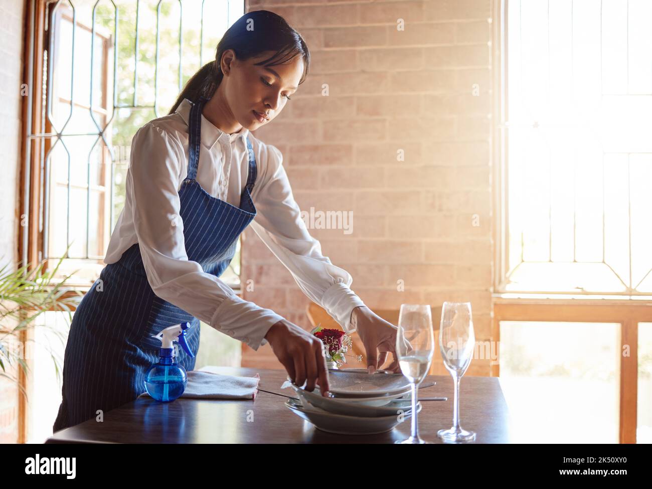 La serveuse du restaurant nettoie les plats de la table après un repas. Le service à la clientèle, le restaurant et le travail dans l'industrie alimentaire comme un serveur de nettoyage sale Banque D'Images