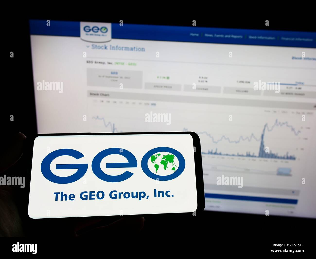 Personne tenant un téléphone portable avec le logo de la société de sécurité américaine The GEO Group Inc. À l'écran en face de la page Web. Mise au point sur l'affichage du téléphone. Banque D'Images