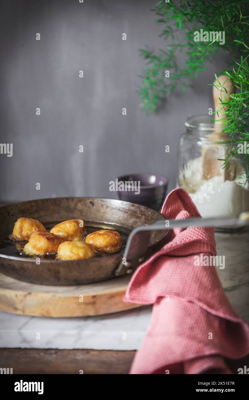 Faire cuire à l'huile les petites bouchées de nonne placées sur une table dans la cuisine à la maison Banque D'Images