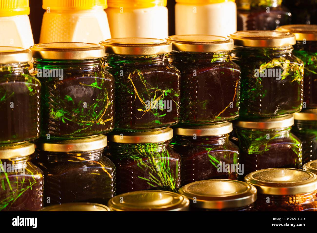 Des bocaux de miel avec des herbes et des aiguilles de pin sibérien se tiennent sur une fenêtre de magasin dans une rangée. Gros plan avec mise au point douce sélective Banque D'Images