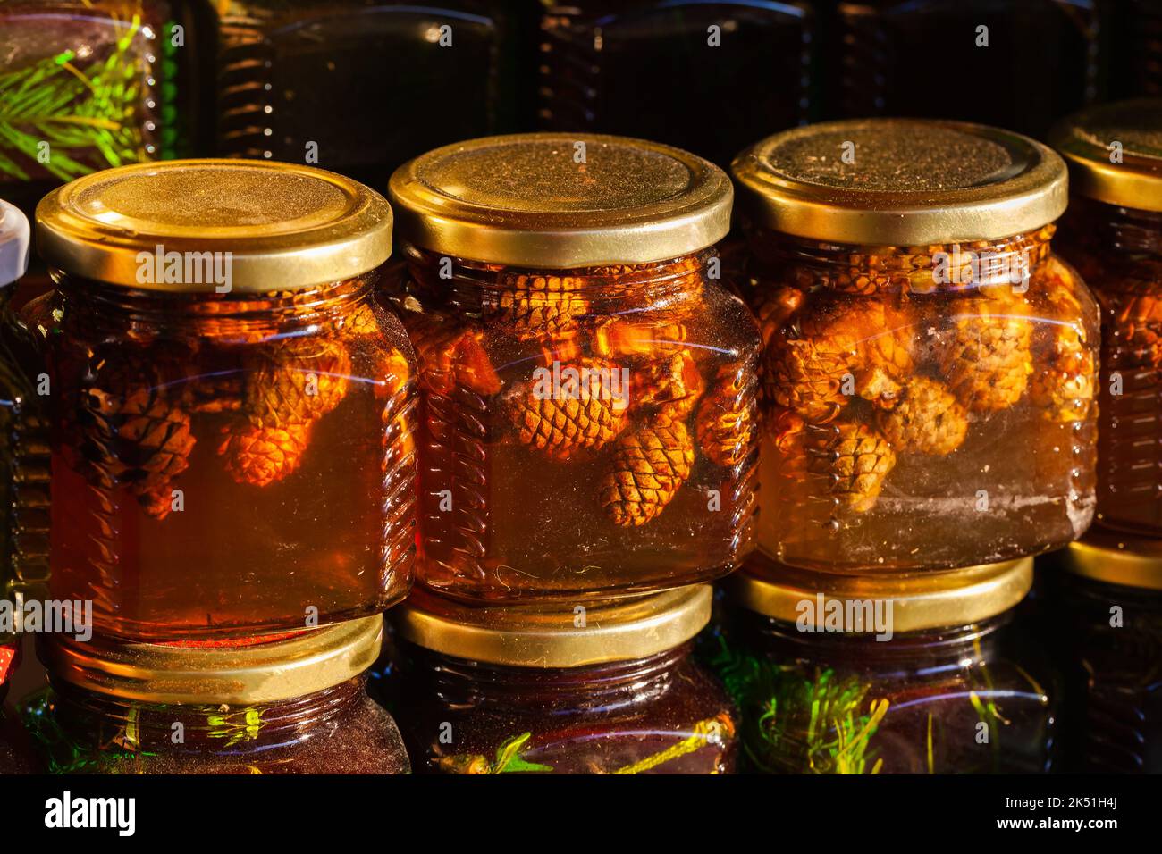 Des jarres de verre de miel avec de petits cônes de pin sibérien se tiennent sur une fenêtre de magasin en rangée. Gros plan avec mise au point douce sélective Banque D'Images