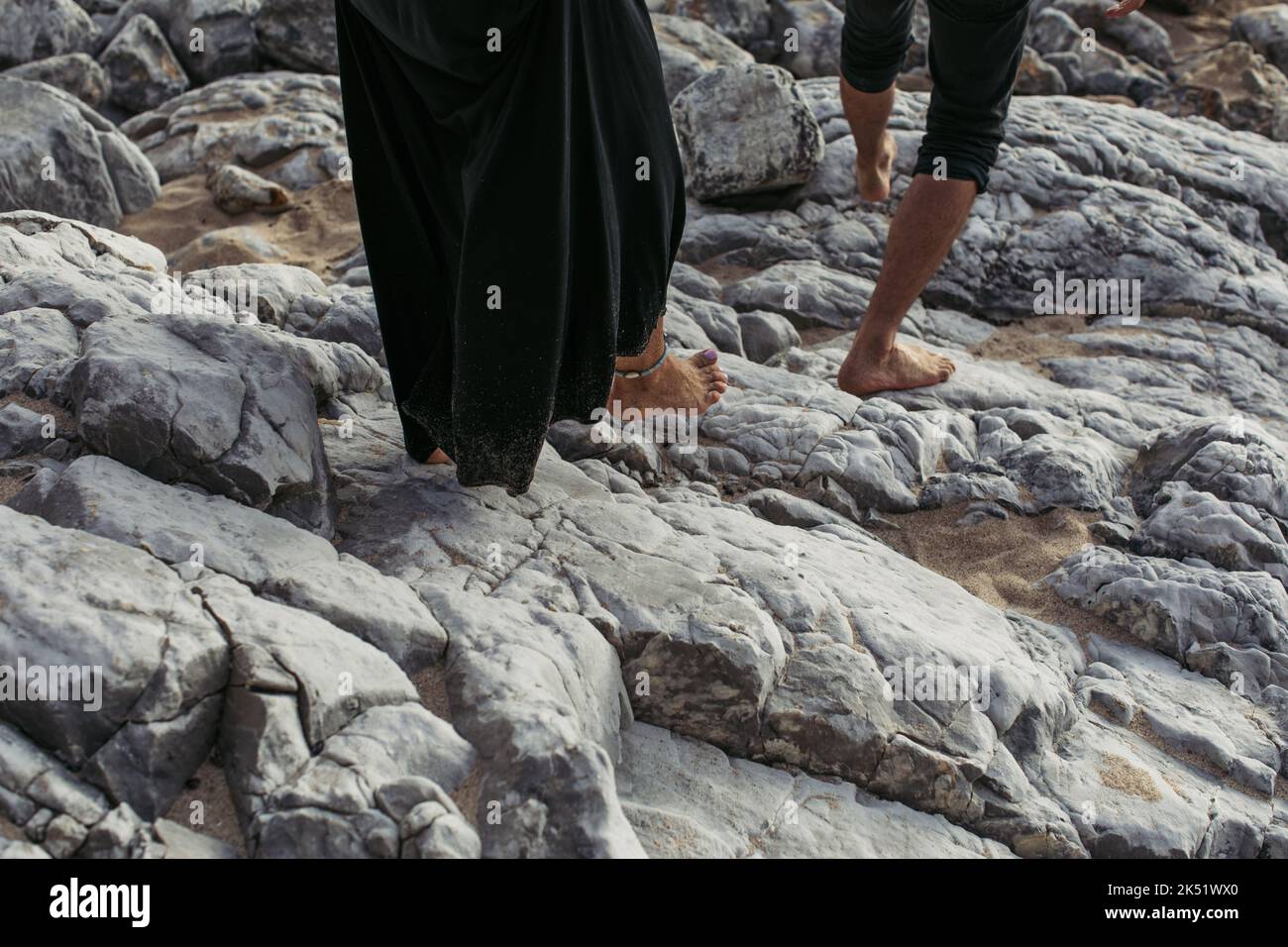 vue rognée de l'homme et de la femme pieds nus avec bracelet de cheville marchant sur des rochers, image de stock Banque D'Images