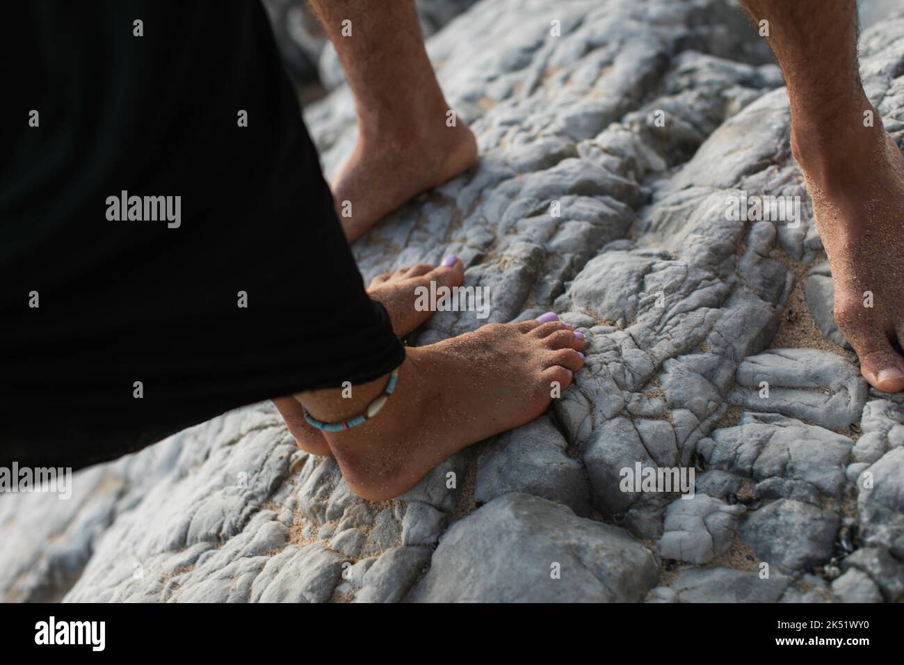 vue rognée de la femme pieds nus avec bracelet de cheville et homme debout sur des rochers, image de stock Banque D'Images