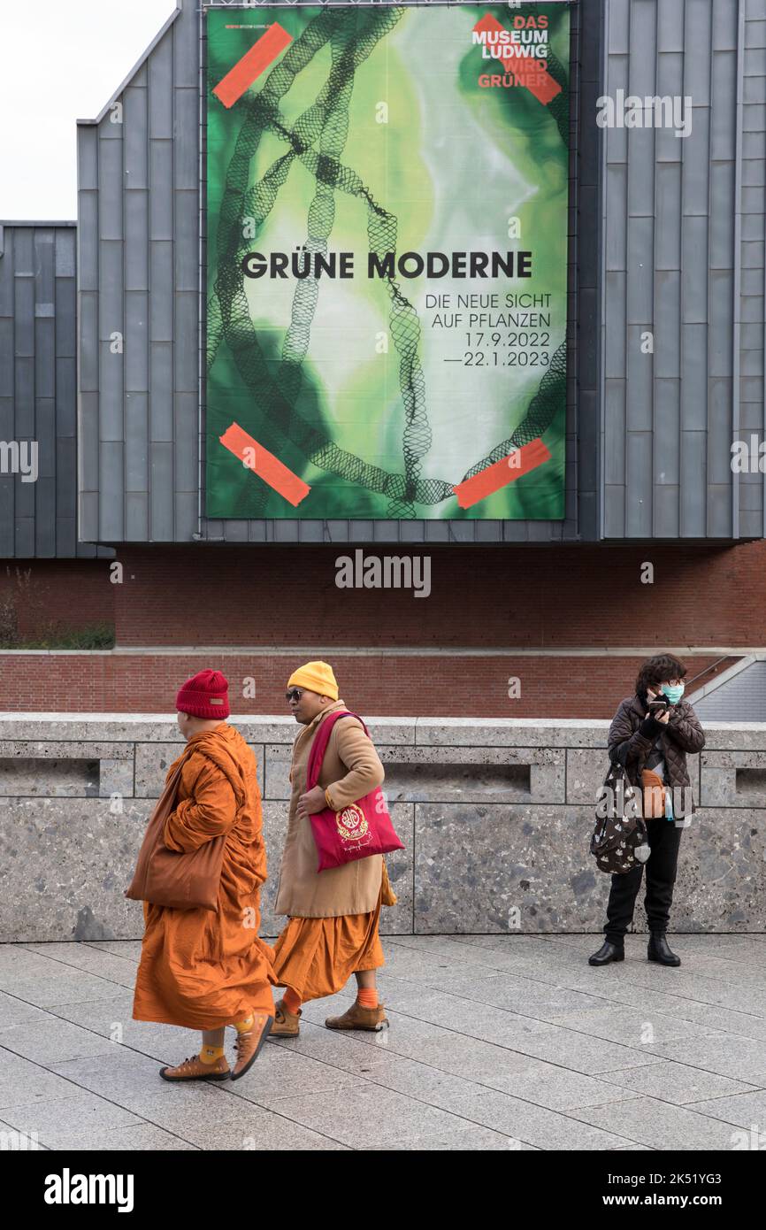 Les moines bouddhistes passent une affiche au Musée Ludwig, Cologne, Allemagne. Buddhistischer Moenche passieren ein Plakat am Museum Ludwig, Koeln, Deutschland. Banque D'Images
