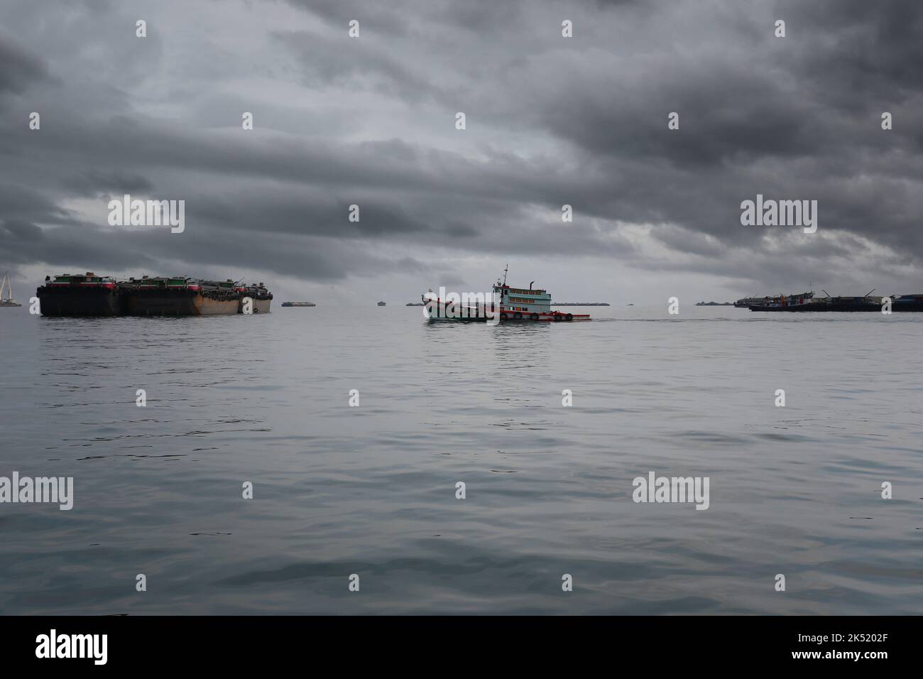 Remorqueurs et cargos amarrés dans la baie de Koh Sichang, province de Chonburi en Thaïlande, ciel couvert et pluie venant. Banque D'Images