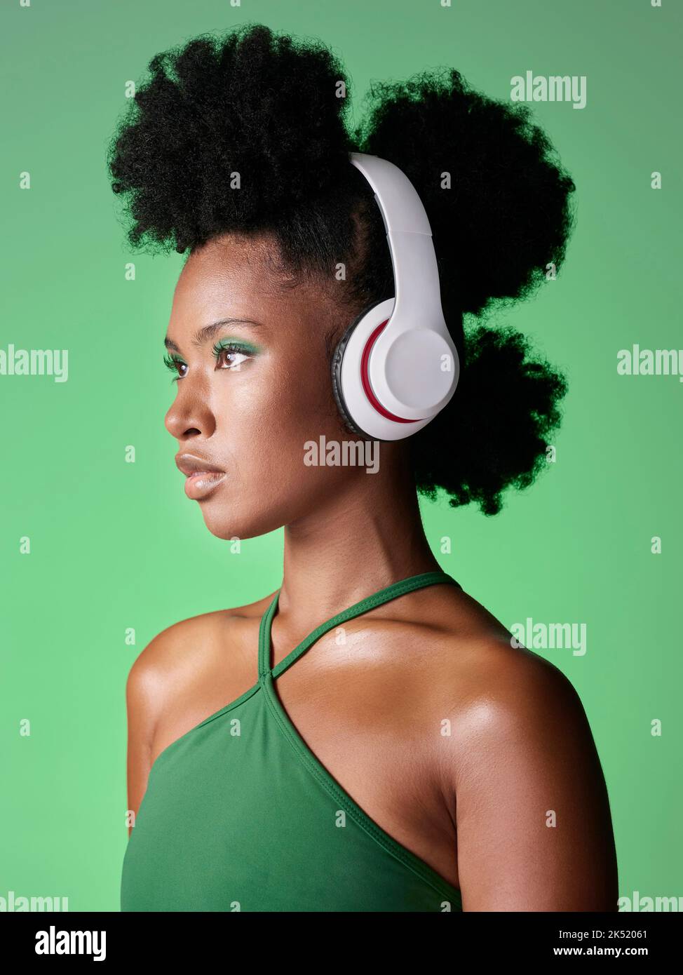 Femme noire avec casque à l'écoute de musique ou podcast sur fond vert studio maquette publicitaire et marketing. Fille africaine de gen z avec audio Banque D'Images