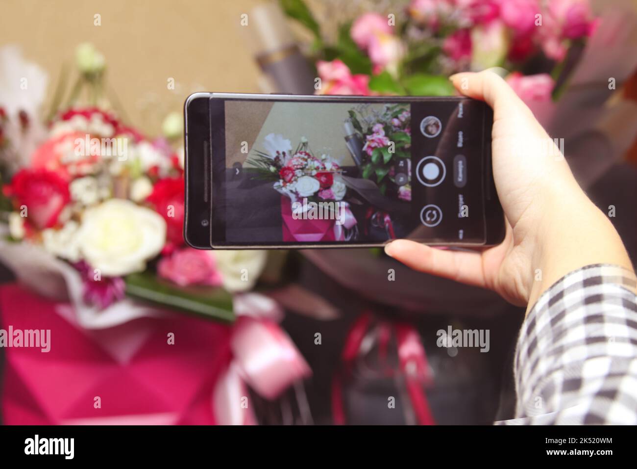 Flou artistique main mâle prendre des photos de roses colorées avec cellulaire, téléphone portable. Femme avec un cadeau de fleurs. Fleuriste femelle avec beaucoup de roses bunches et bou Banque D'Images