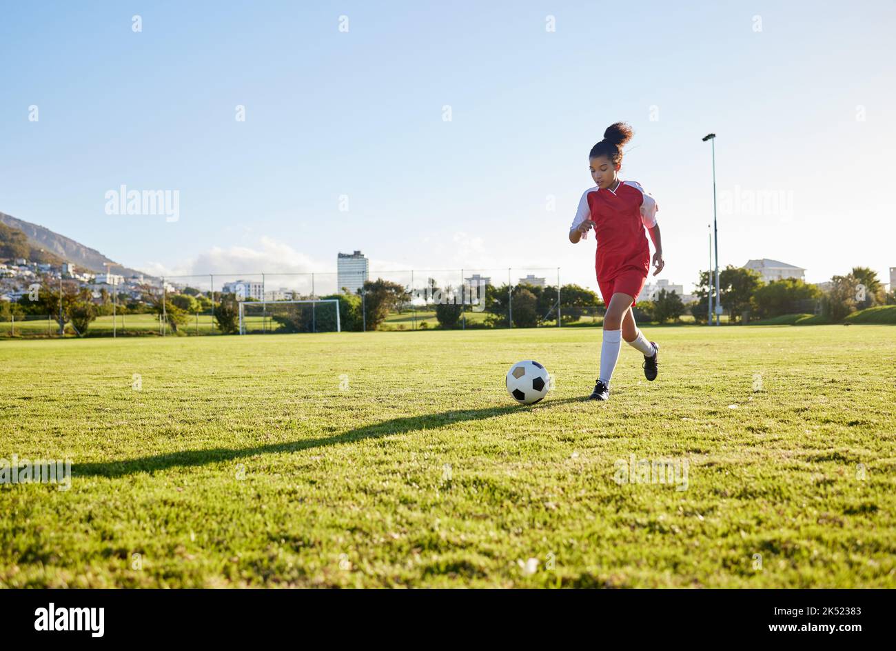 Jeune fille qui court sur gazon, forme de football pour donner un coup de pied au football et énergie d'entraînement des jeunes enfants au Brésil. Enfant en bonne santé, exercice futur de l'athlète Banque D'Images