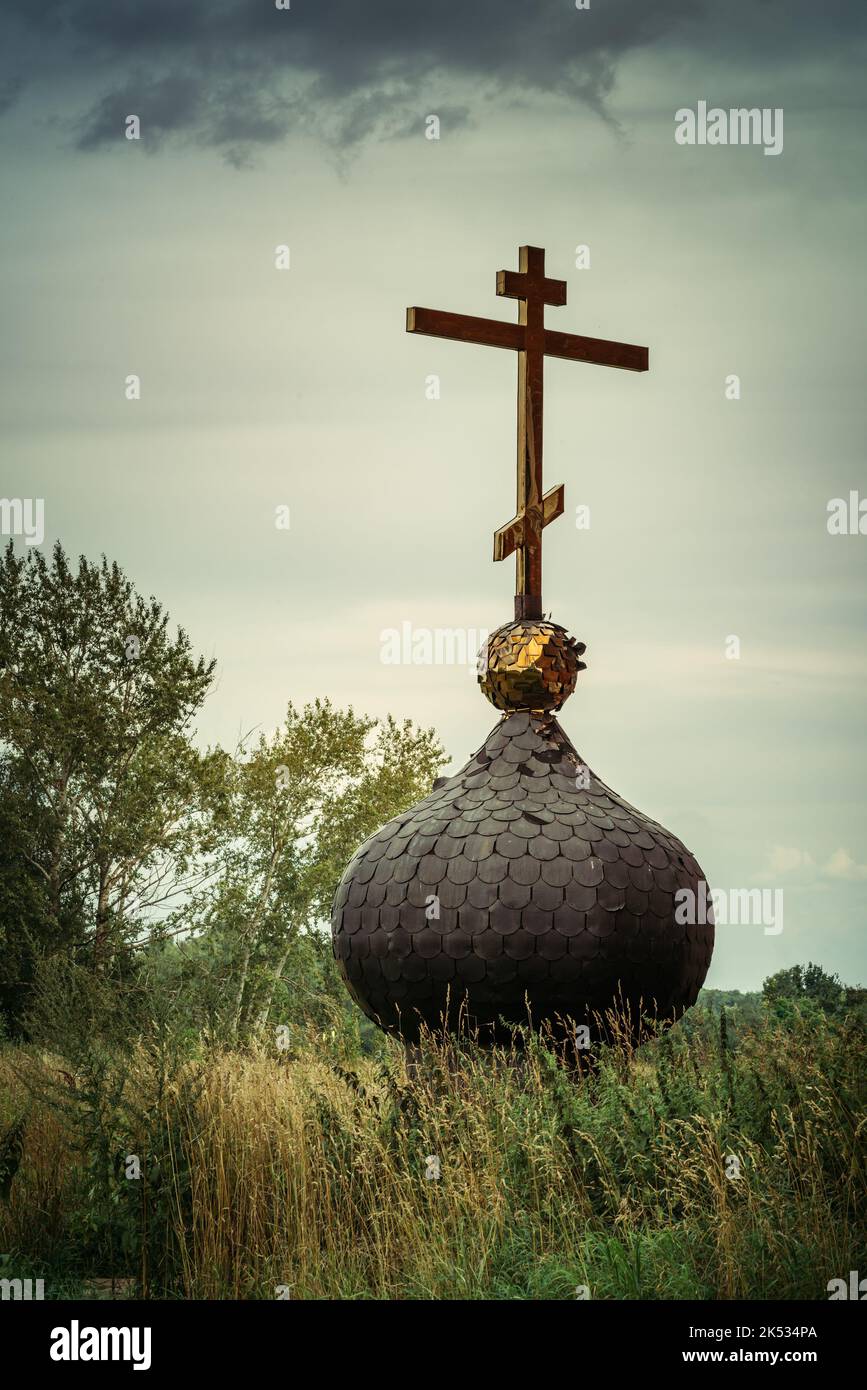 Vieille pointe de chirche russienne avec croix dorée séparée ramener sur le sol et l'herbe sombre moody Banque D'Images