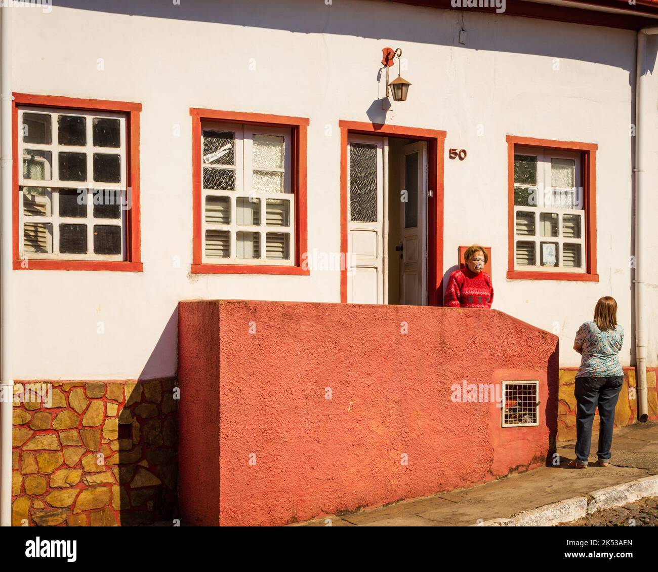 Deux femmes qui parlent devant une maison coloniale à Sadará, Minas Gerais, Brésil. Banque D'Images