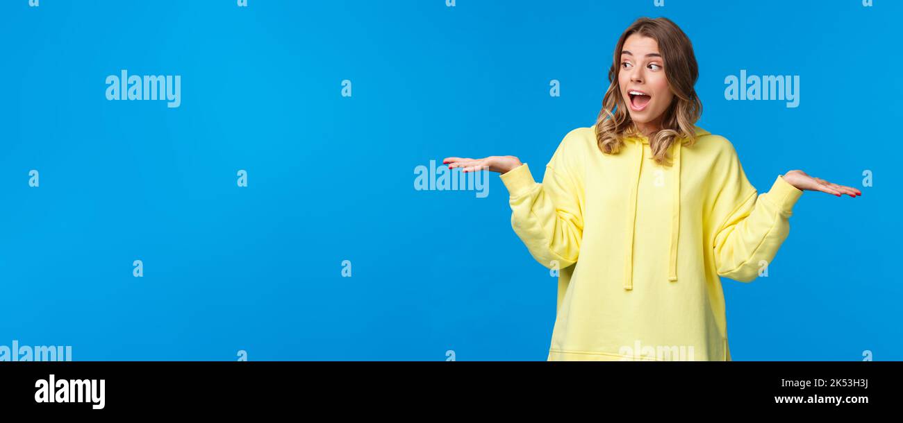 Fille pesant deux choix comme décision de prise, regarder le prélèvement entre les produits qu'elle tient dans les bras du côté gauche et du côté droit, se tenant excité au-dessus Banque D'Images