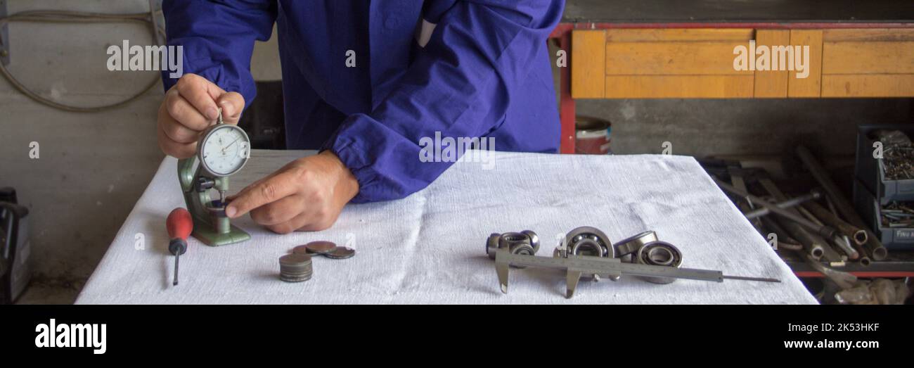 les mains d'un mécanicien dans son atelier qui, avec un instrument de précision de jauge d'épaisseur, mesure les pièces mécaniques. Lié à la mécanique de précision. Banque D'Images
