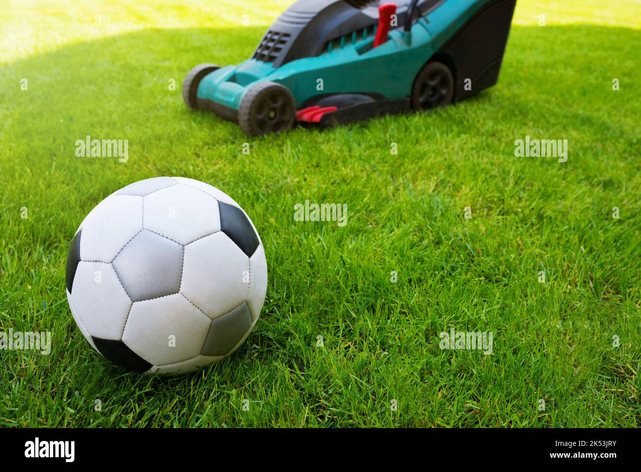 Ballon de football et tondeuse sur un terrain dans l'herbe. Gros plan. Entretien de l'herbe Banque D'Images