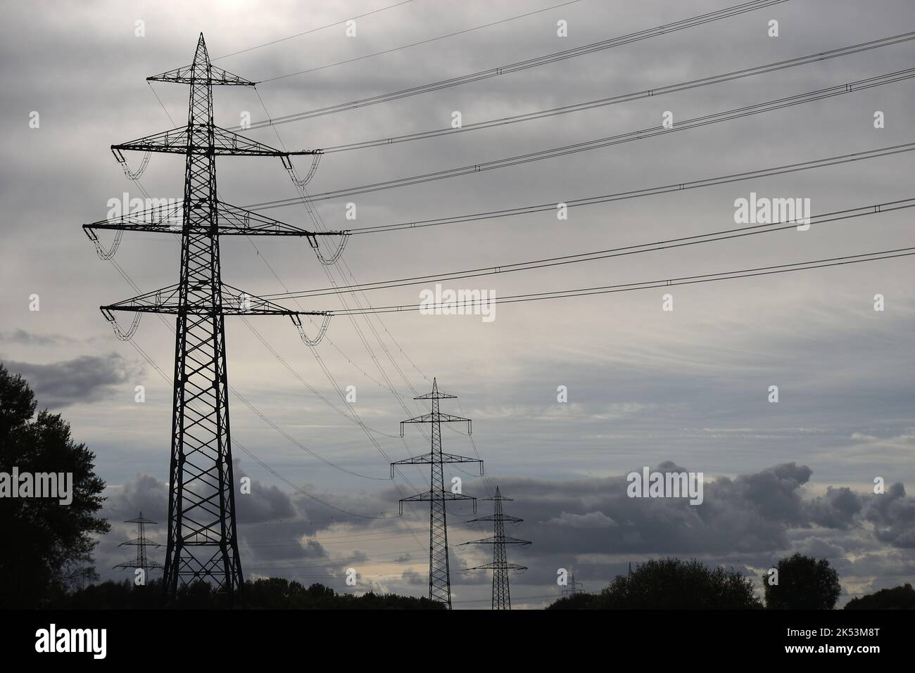 Les silhouettes sombres des lignes terrestres électriques en Allemagne, en Europe. Des nuages sombres symbolisent le changement des chaînes d'approvisionnement en électricité et en énergie dans le monde. Banque D'Images